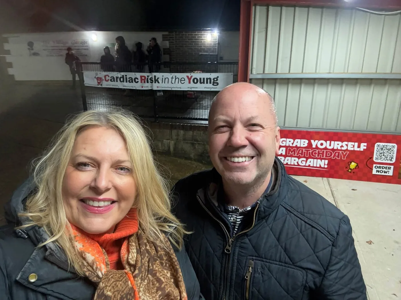 Mims Davies MP at East Grinstead Town FC, a Cardiac Risk in the Young banner on the fence behind her