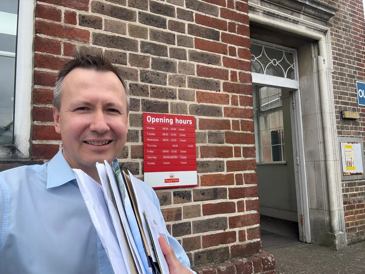 Councillor Matthew Street outside Crowborough Post Office, holding a bundle of post